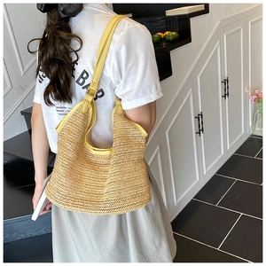 Detail of woven straw tote with yellow leather trim and adjustable metal strap buckle