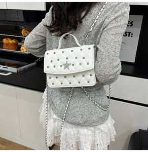 Close-up of white quilted mini bag with sparkling star ornament and silver studs details