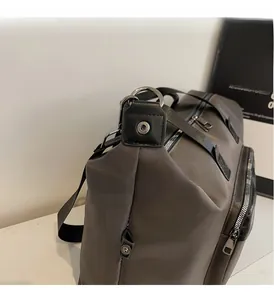Detail of dark brown travel bag featuring nylon fabric and silver metallic hardware
