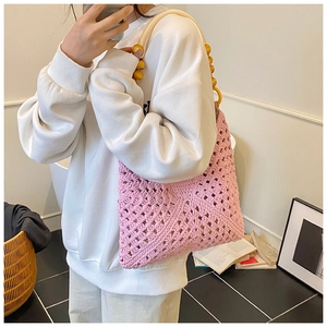 Detail of pink crochet tote bag with decorative wooden beads and woven mesh pattern