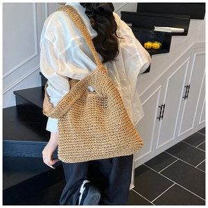 Detailed texture of large straw woven tote bag worn on shoulder for beach style