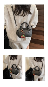 Detail of black bowling handbag with cherry pendant and leather texture for women