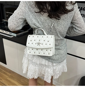 Macro shot of white quilted leather bag with silver star emblem and metal rivet details