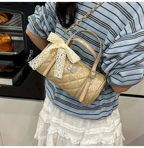 Détail du sac cylindrique beige matelassé avec nœud en dentelle et fermoir rotatif