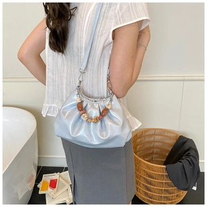 Dettaglio di borsa a secchiello plissettata azzurra con elegante manico di perle