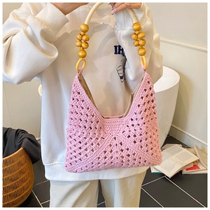 Detalle de bolso tote de ganchillo rosa con asa de cuentas y anillos de madera