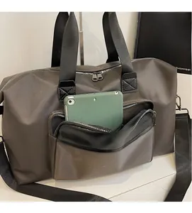 Front zipper pocket of dark taupe travel bag showing storage capacity for a tablet