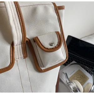 Détail de la toile et du cuir marron sur un sac bandoulière avec bouton pression en métal