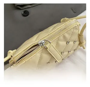 Detailed close-up of quilted cream crossbody bag with silver studs and zipper detail