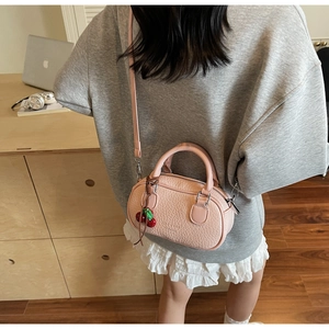 Close-up of pink mini pillow bag with lychee texture and cute cherry pendant
