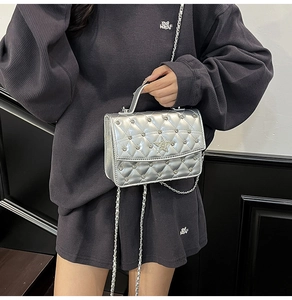 Détails du sac bandoulière argenté avec rivets étoiles et motif matelassé en strass