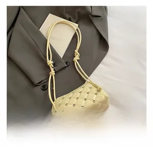 Detail of beige quilted shell bag with sparkling rhinestones and knotted shoulder strap
