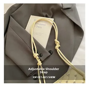 Detail of adjustable knotted shoulder strap on cream quilted shell bag with silver rivets