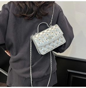 Detail of silver quilted chain bag with rhinestone star emblem worn by a model