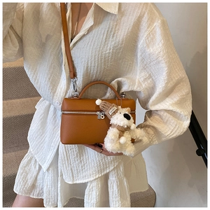 Dettaglio borsa a scatola in pelle marrone con motivo litchi e ciondolo a forma di orso