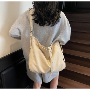 Close-up of minimalist cream canvas tote bag with adjustable metal eyelet strap