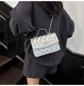Détail du sac argenté matelassé avec motif en strass et fermoir étoile porté à l'épaule