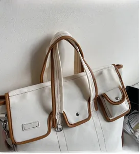 Détails du sac fourre-tout en toile montrant les bordures en cuir brun et boucles