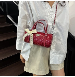 Détail du sac cylindrique matelassé rouge avec nœud en dentelle et fermoir argenté