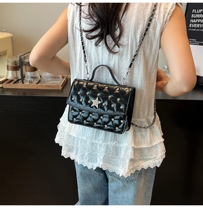 Détail d'un sac bandoulière noir matelassé avec étoile argentée porté par un mannequin