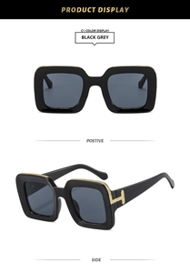 Detail of square sunglasses with gold T-shaped metal hinges and thick black frames