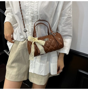 Détail du sac à main marron matelassé avec nœud en dentelle et bandoulière en chaîne