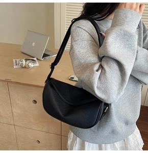 Détail d'un sac demi-lune en cuir noir grainé avec boucle de réglage en métal doré