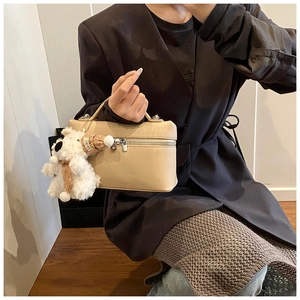Dettaglio borsa a tracolla beige texture litchi con ciondolo a forma di cane di peluche