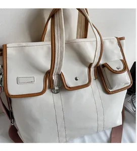 Détail du sac cabas en toile blanc cassé avec bordure en cuir brun et poches