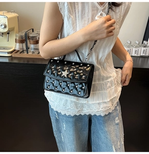 Close-up of black quilted bag with silver studs and star buckle in a cafe setting