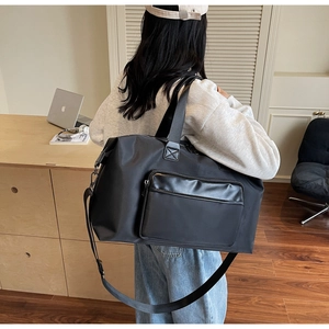 Black large capacity travel bag with nylon fabric and adjustable strap shown on a table