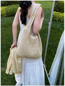 Detail of hand-woven beige straw tote bag showing fine texture in natural outdoor setting