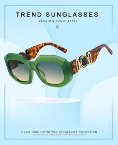 Detail of green acetate frame sunglasses with gold hinge decor and gradient lenses