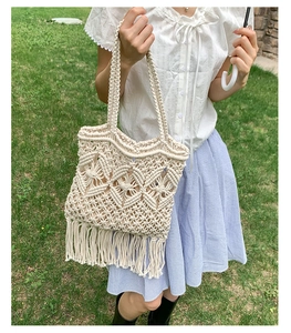 Detail of bohemian woven tote bag with fringe trim on a natural green grass field