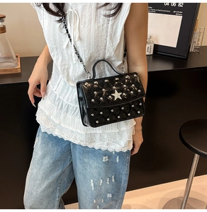 Detail of black quilted crossbody bag with silver star and studs on a female model