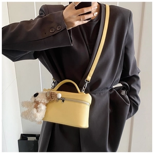 Piccola borsa quadrata gialla in pelle con ciondolo a cucciolo indossata a tracolla