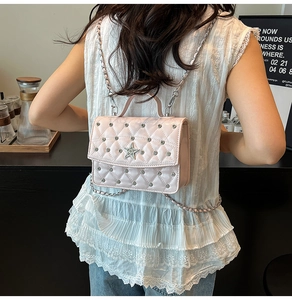 Close-up of pink quilted crossbody bag with silver star and rivet metal decorations