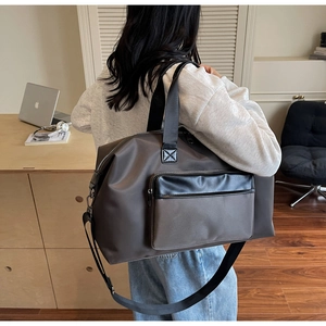 Deep brown large travel bag with adjustable strap shown in a modern home office setting