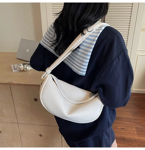 Détail du sac demi-lune blanc en cuir texturé avec bandoulière réglable sur le côté