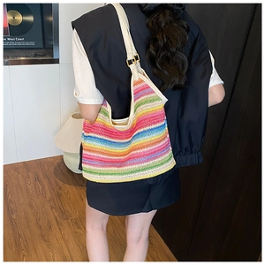 Detail of colorful woven beach bag featuring vibrant rainbow stripes and leather strap