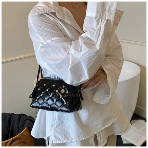 Detail of black glossy quilted shoulder bag with silver studs and elegant chain strap