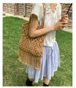 Detailed macro view of macrame woven tote bag featuring long fringes and boho diamond pattern
