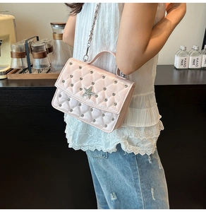 Detailed macro view of pink quilted handbag with rhinestone stars and chain strap