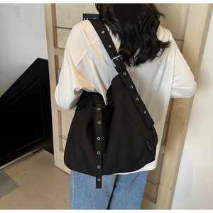 Side view of the large black canvas hobo bag with eyelet wide strap on female model