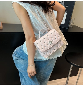Détail du sac à bandoulière rose matelassé avec poignée perle et clous étoilés argentés