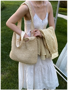 Detailed texture of beige hand-woven tote bag shown on model in outdoor setting