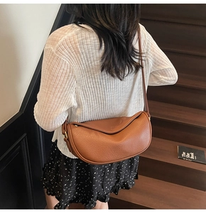 Détail du sac bandoulière en cuir caramel avec texture grainée et boucle en métal doré