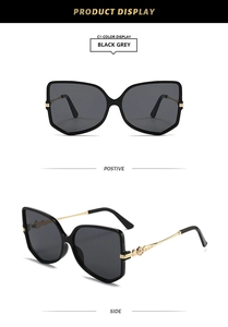 Detail of butterfly frame sunglasses with gold vintage embossed metal temples and grey lenses