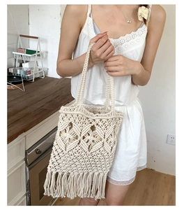 Detail of hand-woven cream tote bag featuring diamond hollow patterns and long tassels