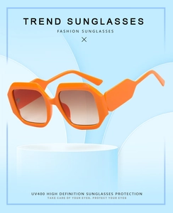 Detail of orange polygonal sunglasses with UV400 protection on a blue geometric base